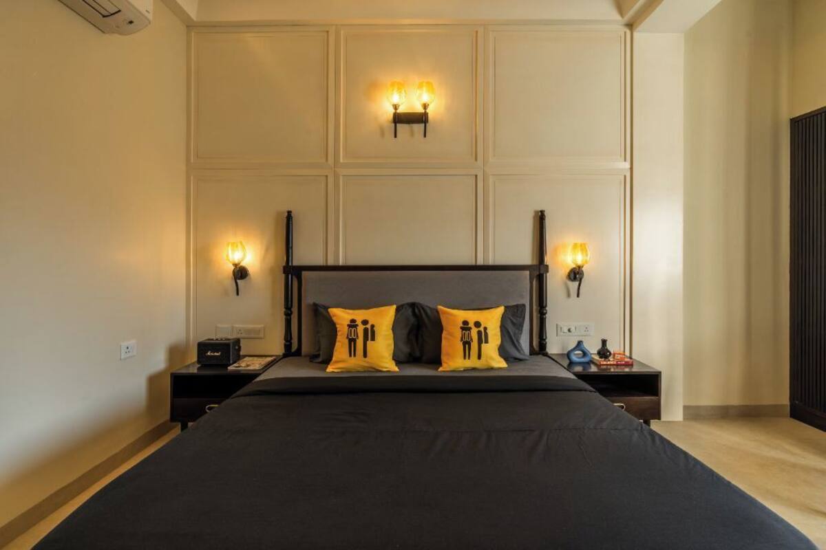A bedroom with a large bed, two bedside lamps, and a wall-mounted light fixture.