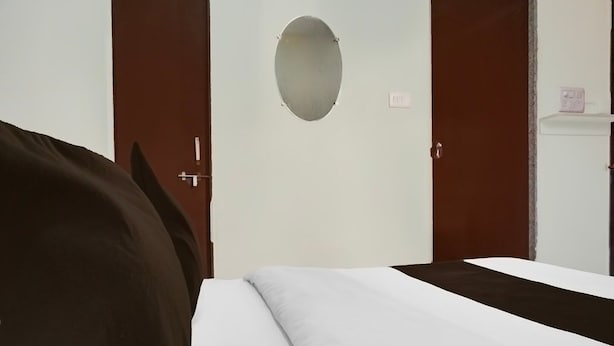 Una camera d'albergo con un letto, un armadio e un tavolino con una presa elettrica.