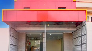 Un ingresso di un edificio con una sporgenza rossa, una scala che conduce all'ingresso e un muro in mattoni su un lato.