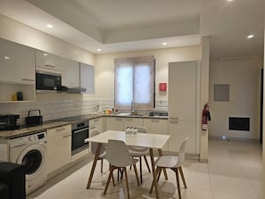 A modern kitchen with a dining area, built-in appliances, and a fire extinguisher. - Hawana Salalah - Private studio with mountain view and swimming pool (Salalah)