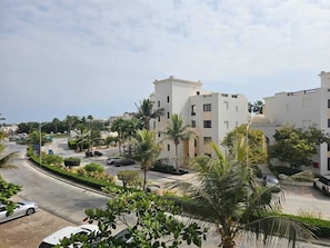 A residential area with modern buildings, a curved road, and palm trees. - Hawana Salalah - Private studio with mountain view and swimming pool (Salalah)
