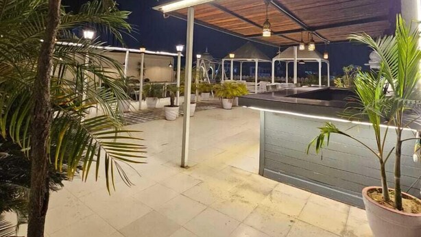 An outdoor patio area with a covered seating area, potted plants, and a pool. - Manuhar (Jaipur)