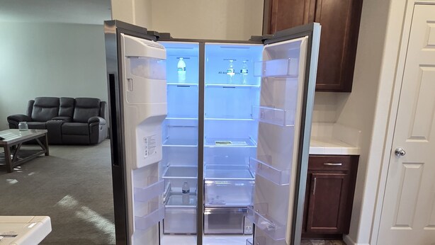 Eine moderne Küche mit integriertem Kühlschrank, einem Essbereich inklusive Tisch und Stühlen sowie einem dunklen Holzschrank.