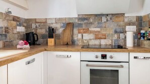 Een moderne keuken met witte kasten, een houten aanrecht en een mozaïek achterwand.