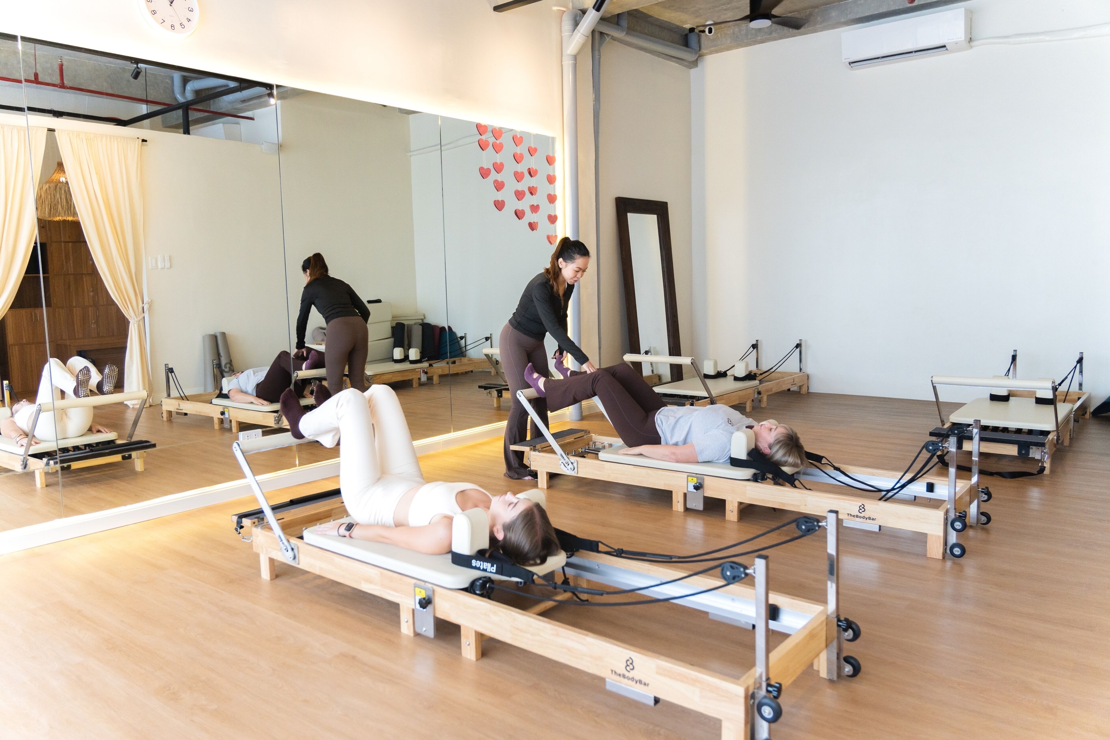 Un estudio de Pilates con varias mesas de ejercicio y espejos.