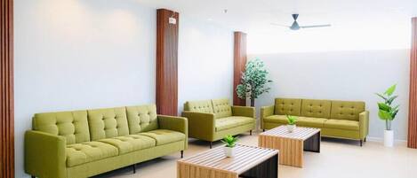 A modern living room with a sofa, armchairs, a coffee table, and a ceiling fan.