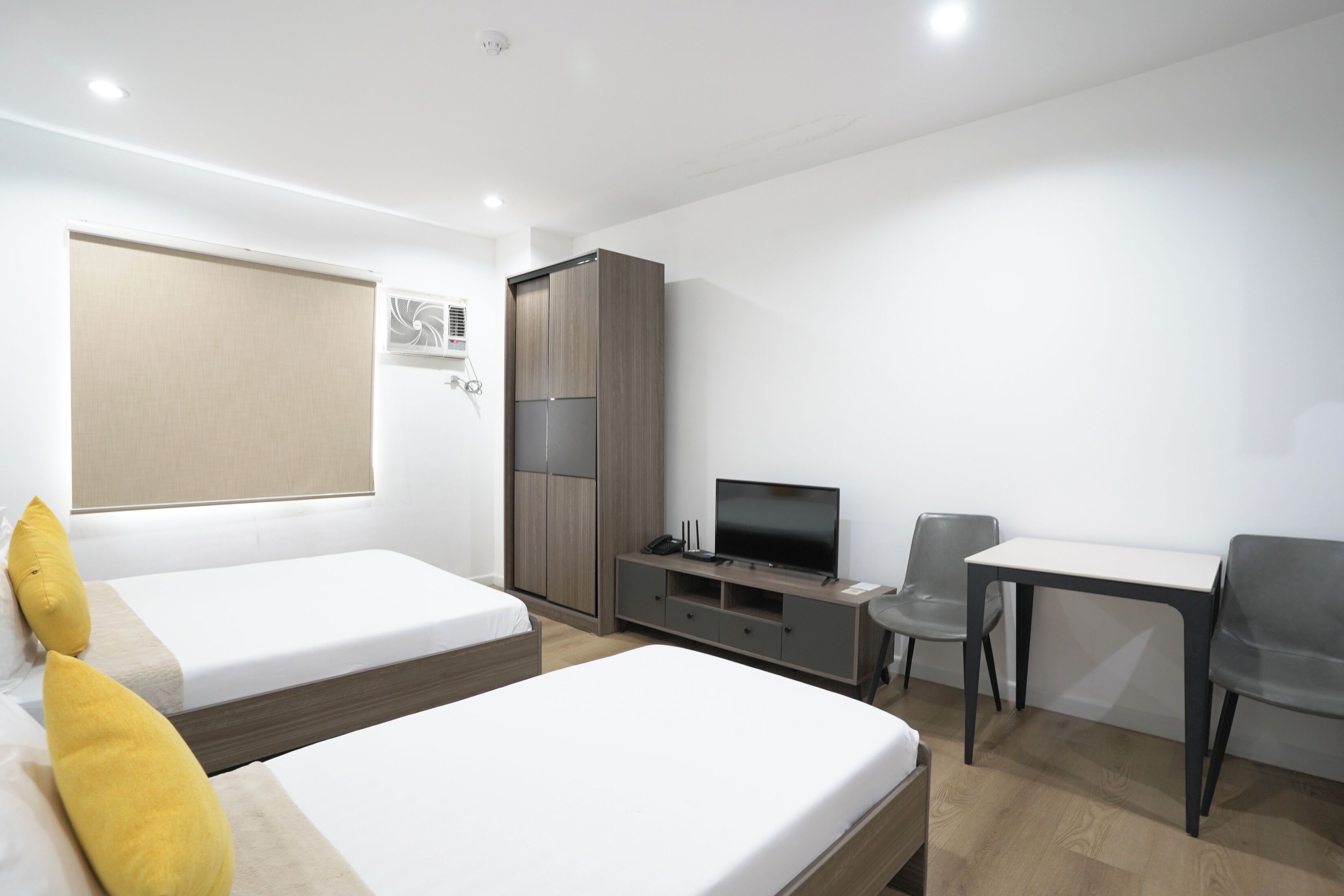 A hotel room with two beds, a TV, a desk, and a chair.