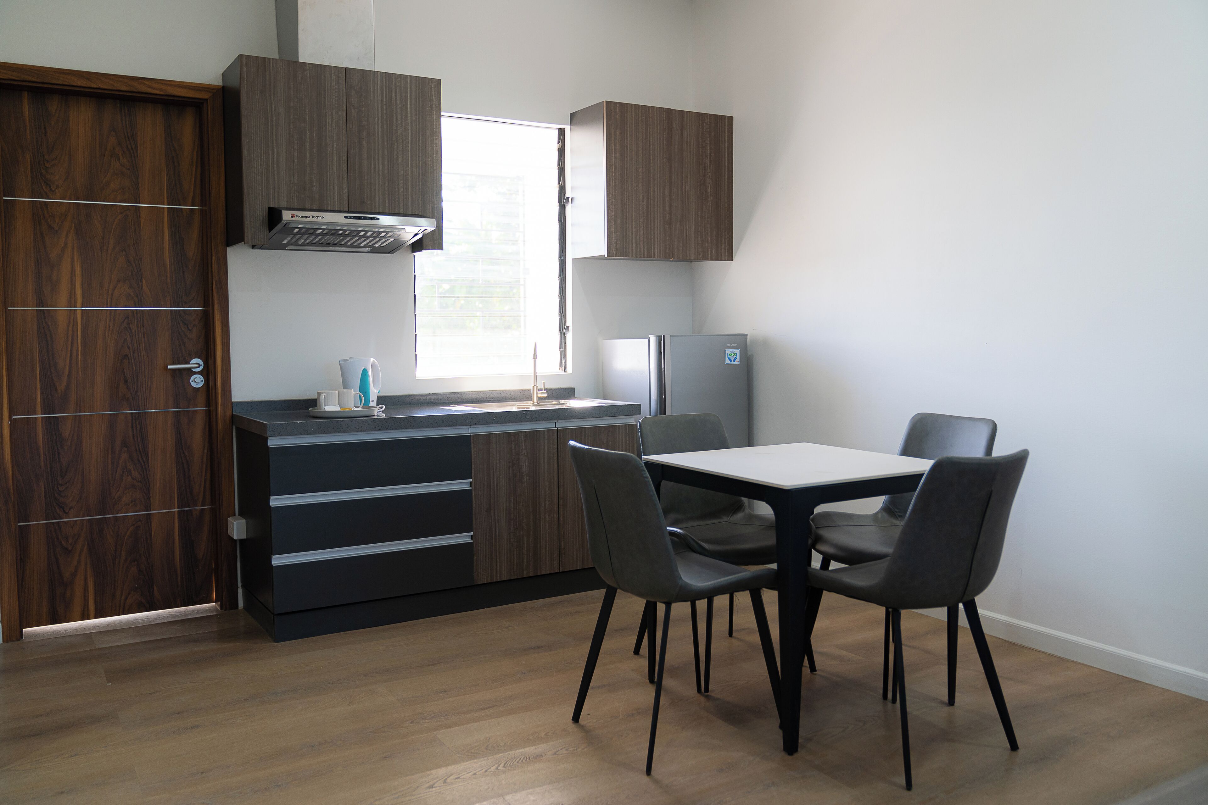 A compact kitchen with a built-in stove, a refrigerator, and a dining area with chairs and a table.