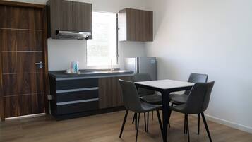 A compact kitchen with a built-in stove, a refrigerator, and a dining area with chairs and a table.