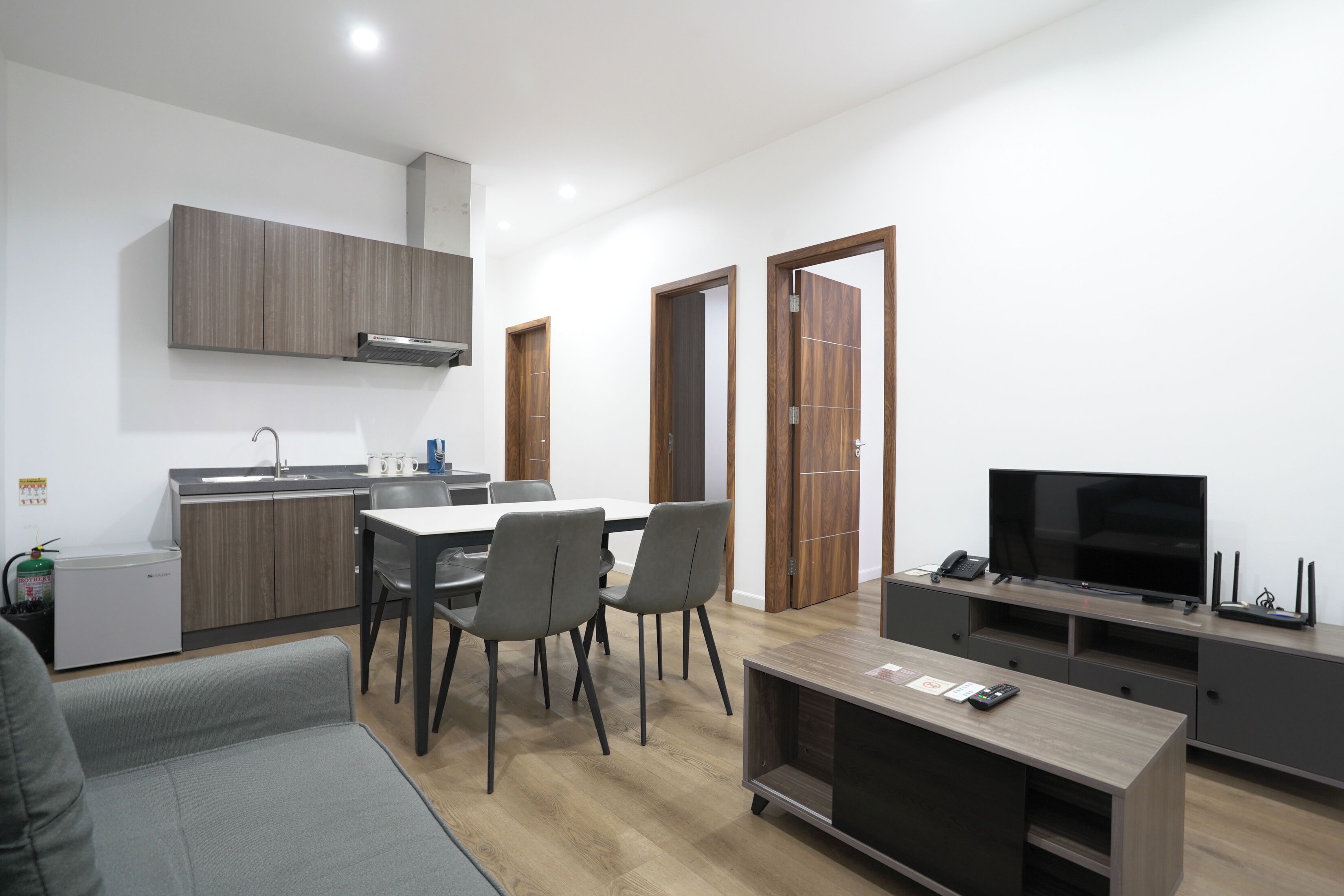 A modern kitchen with a dining area, a TV, and a sofa.