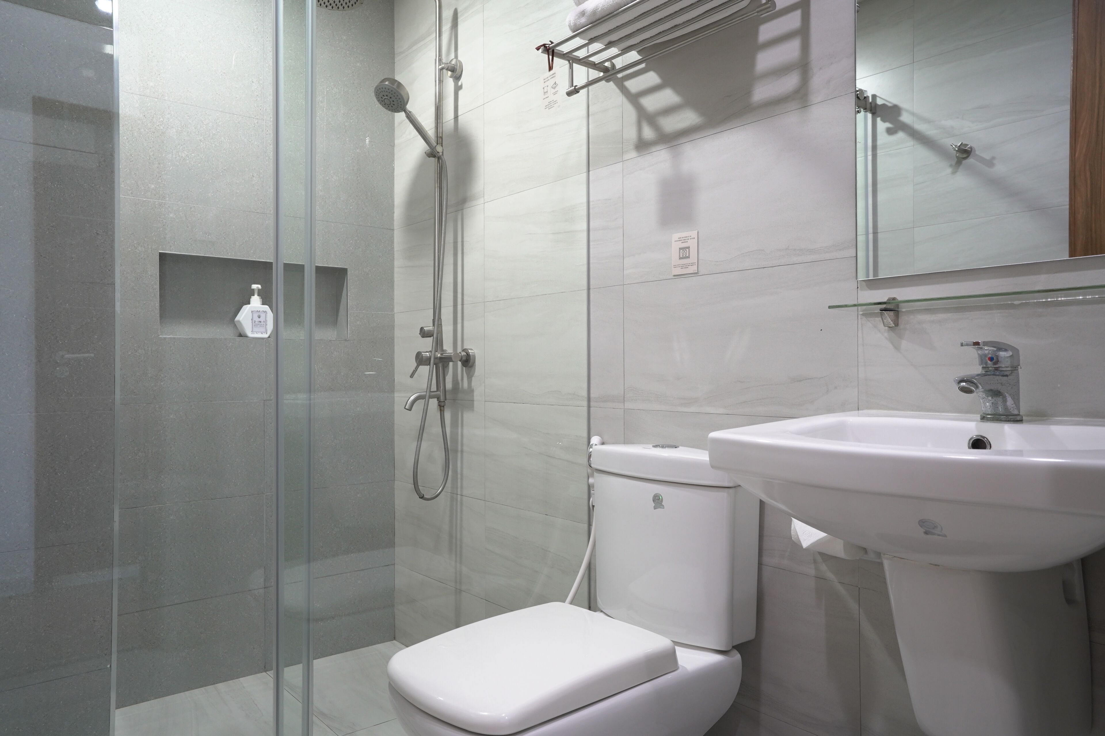 Ein modernes Badezimmer mit Duschkabine aus Glas, einer weißen Toilette und einem Waschbecken auf Säule.