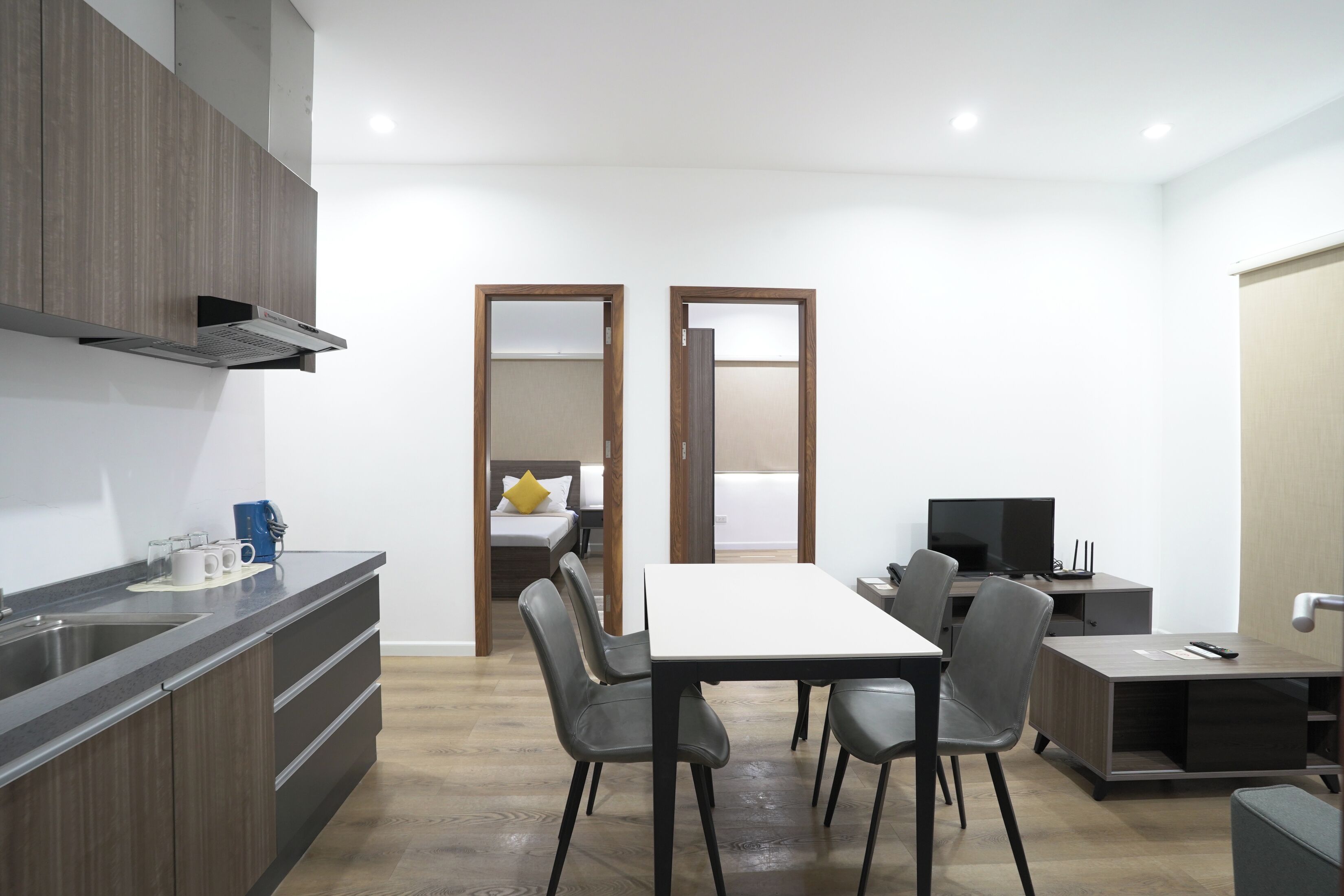 A modern kitchen with a built-in stove, a dining area with a table and chairs, and a separate living area with a TV and seating.
