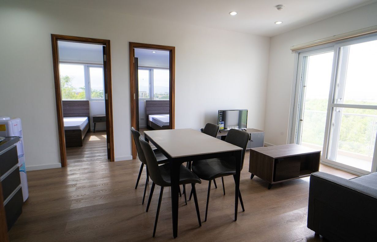 Une pièce moderne avec un plancher en bois, une table à manger avec des chaises, un téléviseur et une grande fenêtre.