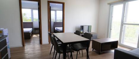 Une pièce moderne avec un plancher en bois, une table à manger avec des chaises, un téléviseur et une grande fenêtre.