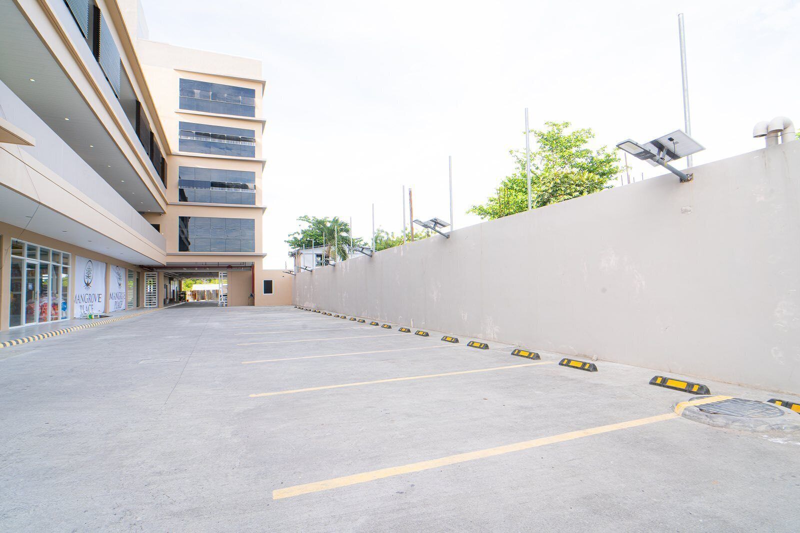 Un estacionamiento con un edificio que tiene grandes ventanales y paneles solares en el techo.