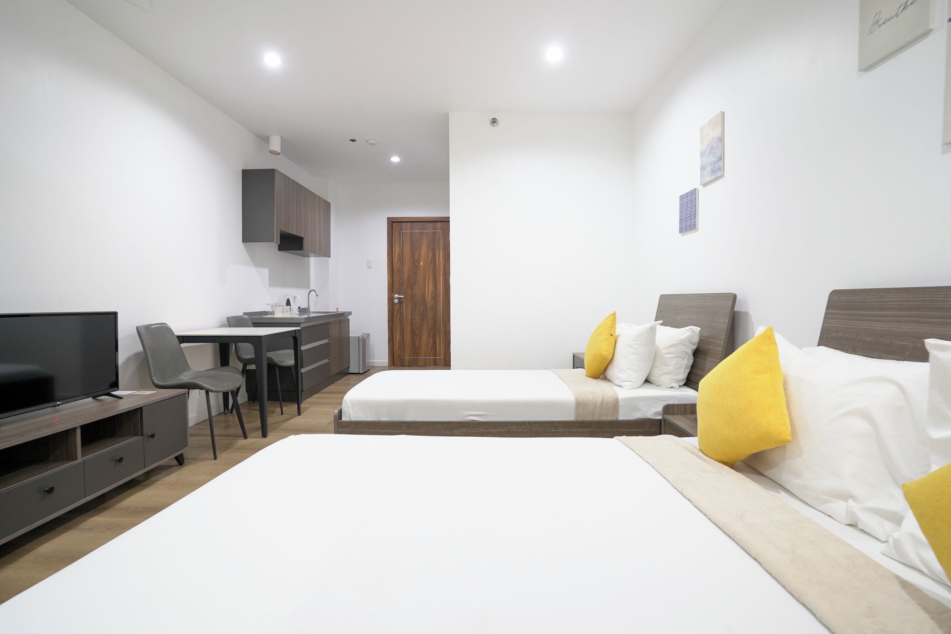 A modern hotel room with a bed, a desk, a television, and a wardrobe.