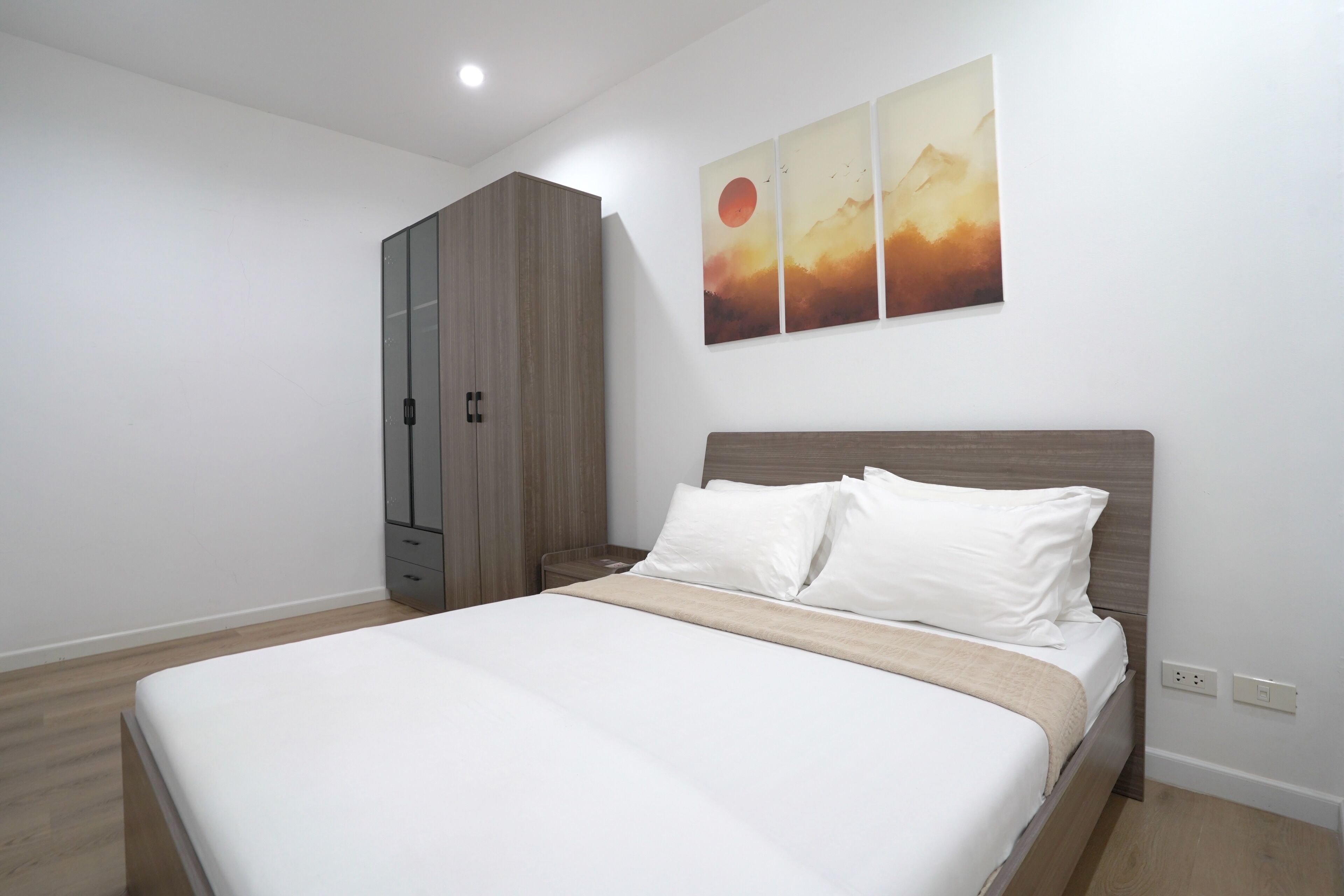 A bedroom with a bed, a wardrobe, and a wall-mounted artwork.