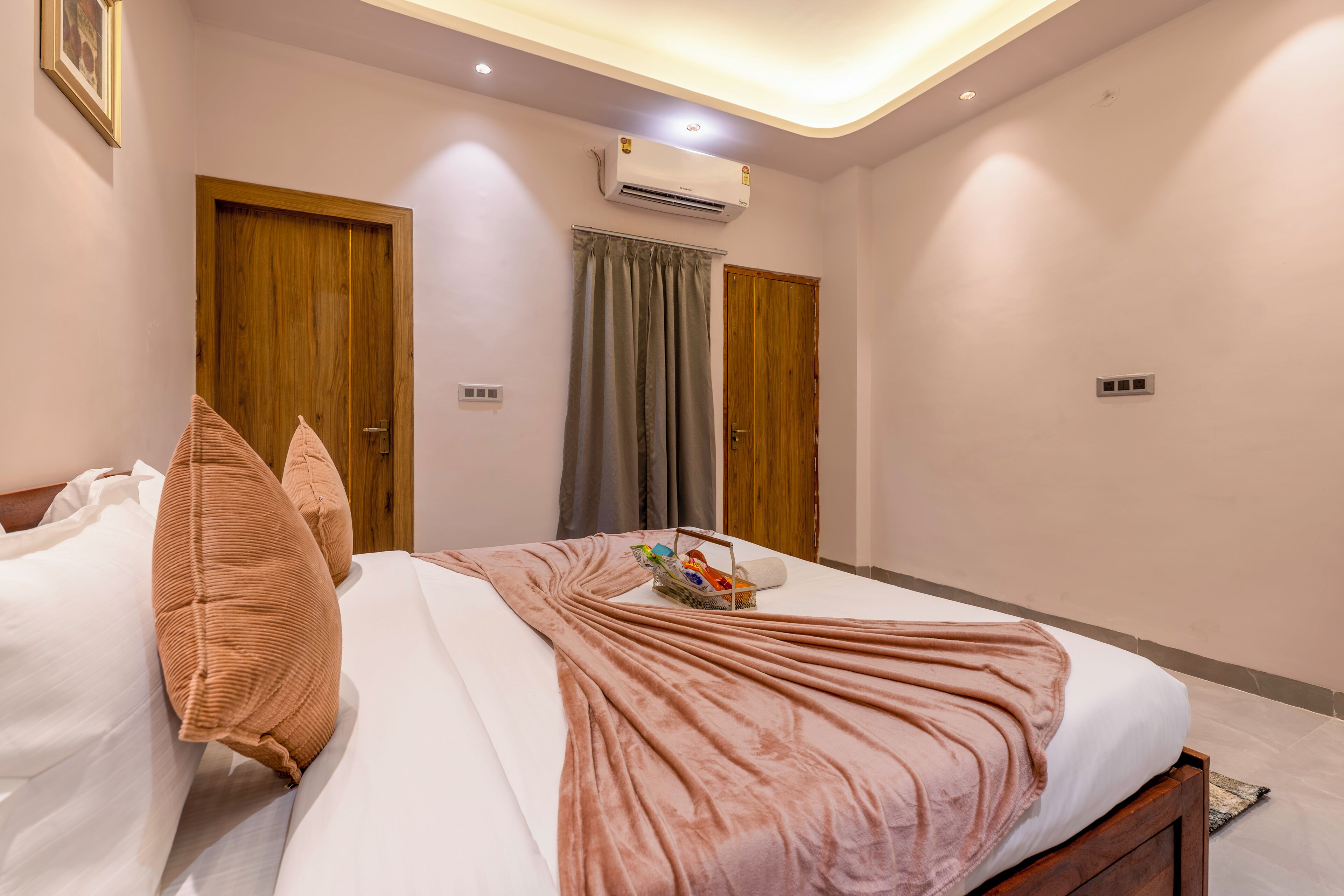 A bedroom with a bed, a wooden door, an air conditioning unit, and a window with curtains.