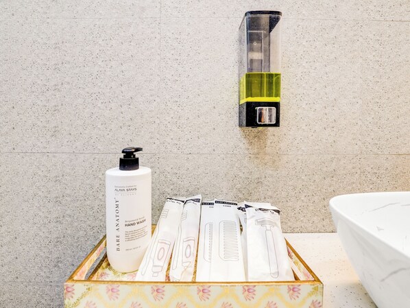 Une salle de bain équipée d’un distributeur de savon liquide, d’une bouteille de savon et d’une boîte de produits de toilette.