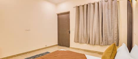 A bedroom with a bed, a ceiling fan, a door, and curtains.