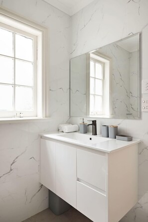 A bathroom with a white marble vanity, a large mirror, and a window. - 4BR Surry Hills Home | Pet Friendly + Parking (Surry Hills)