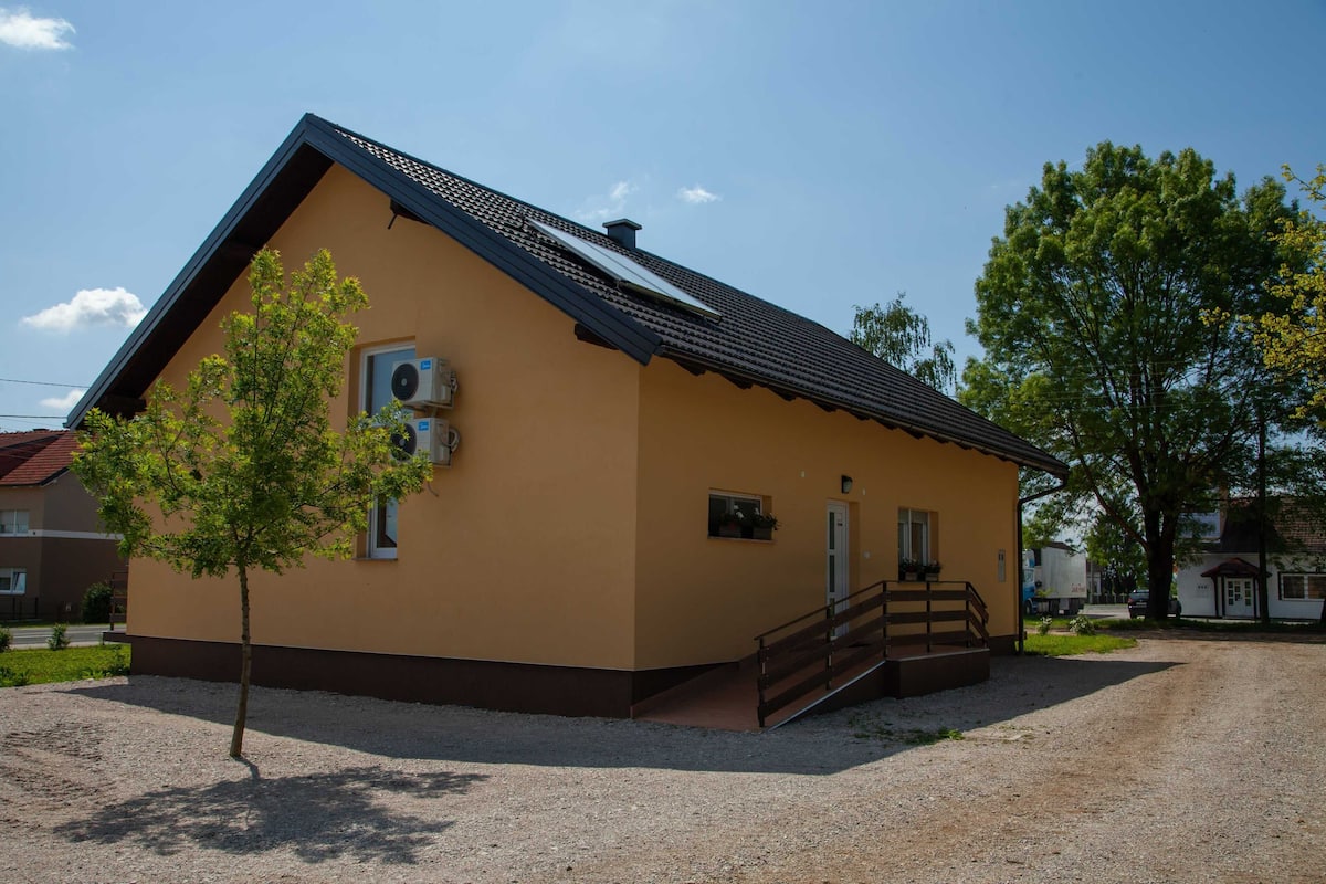 A single-story building with a sloped roof, a small porch, and a gravel driveway.