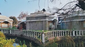 Un edificio tradizionale con un ponte in pietra che sovrasta un corpo d'acqua, immerso nel verde.