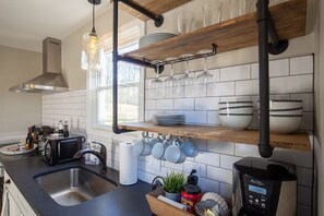 Cozinha moderna com forno embutido, cafeteira e pia.