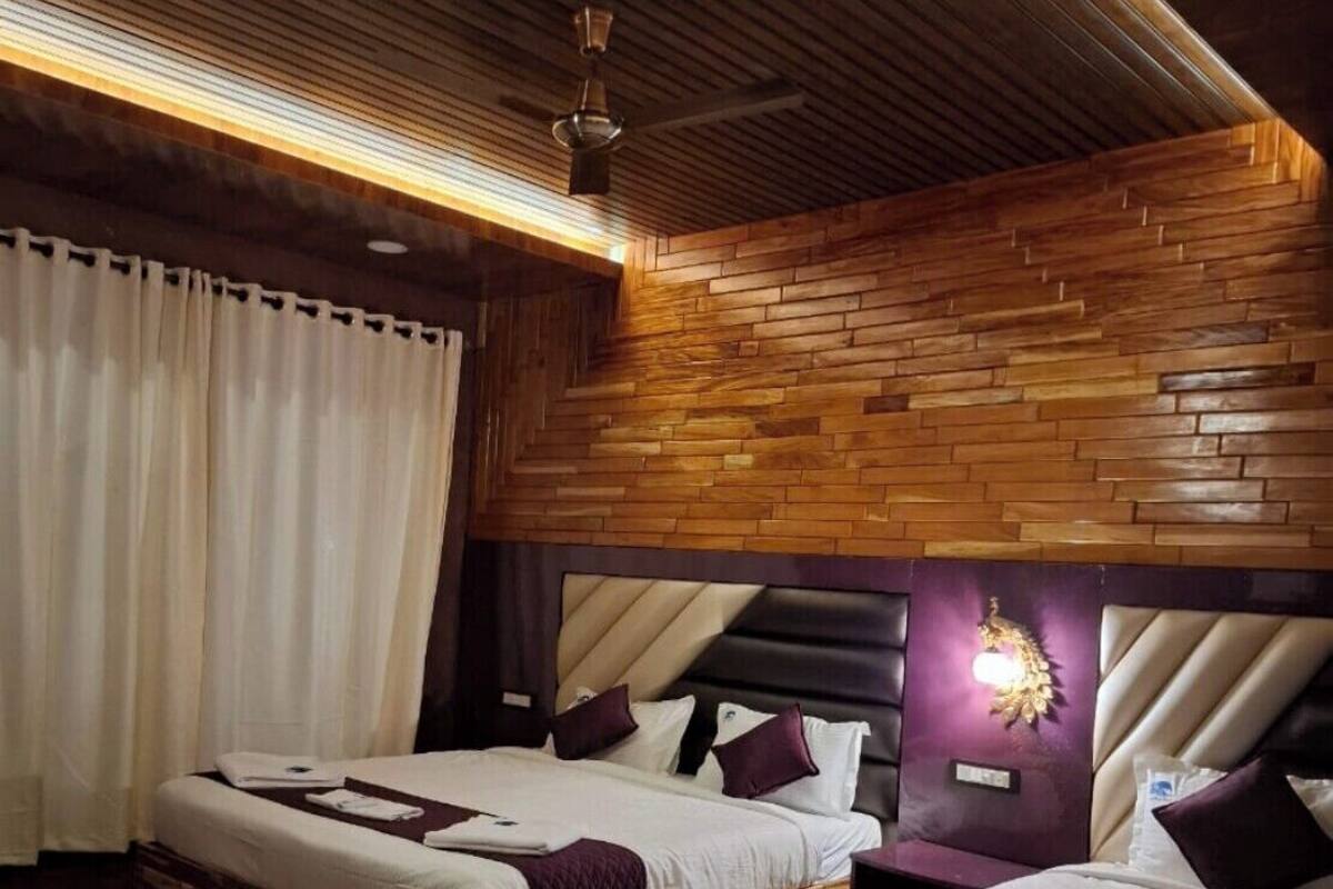 A modern bedroom with two beds, wooden paneling, and a ceiling fan.