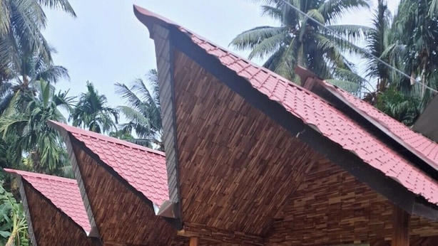 Une structure en bois dotée d’un toit en pente, d’un espace extérieur aménagé avec des chaises et d’un chemin pavé.