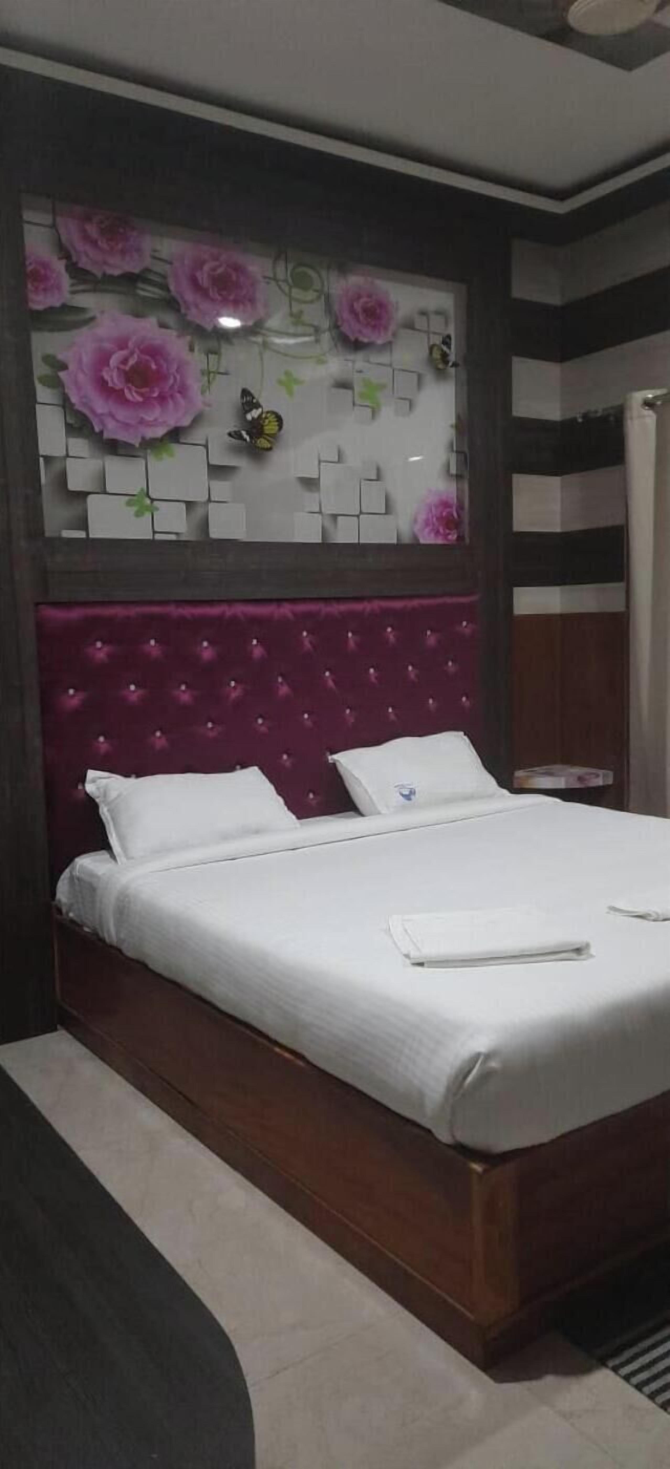 A modern bedroom with a wooden bed, white bedding, and a decorative headboard with floral patterns.