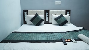 Een net opgemaakt bed met een gewatteerde sprei, twee kussens en een afstandsbediening op het bed.