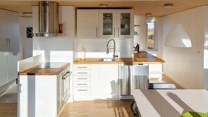 A modern kitchen with white cabinetry, stainless steel appliances, and a wooden countertop. - 3 bedroom amazing home in Brovst (Brovst)