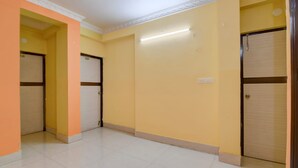 Un pasillo con dos puertas cerradas, una con una cerradura visible, y un accesorio de iluminación en la pared.