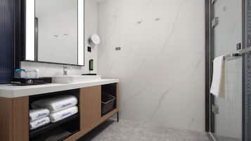 Un baño moderno con un espejo grande, un lavamanos y una zona de ducha.