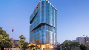 A modern high-rise hotel with a curved facade, multiple floors, and a prominent entrance with a canopy. - Hampton by Hilton Jinjiang Airport (Quanzhou)