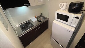 Cocina compacta con estufa a gas, microondas y un lavamanos pequeño.