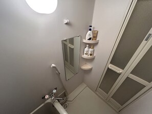 Een bad/douchecombinatie, een haardroger, handdoeken, zeep