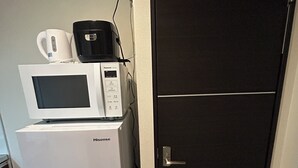 Una cocina compacta con un refrigerador blanco, un microondas y una cafetera.