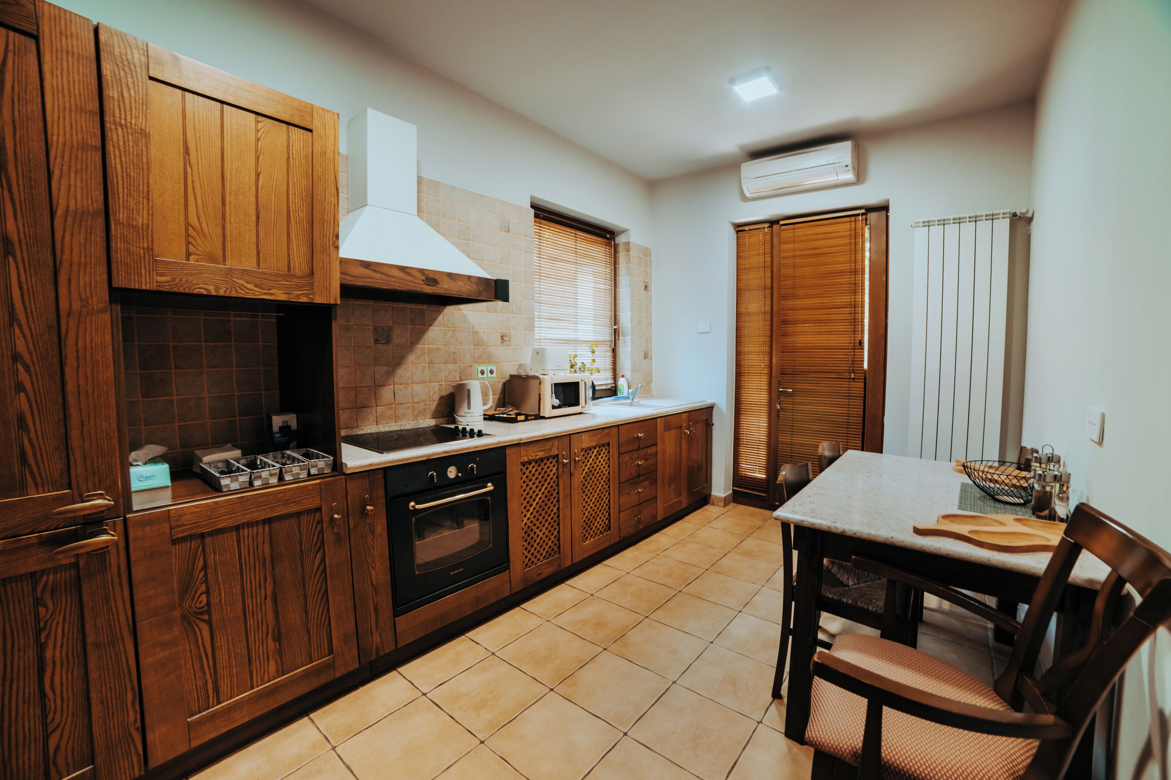 A kitchen with wooden cabinets, a stove, and a dining table with chairs.