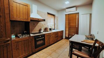 A kitchen with wooden cabinets, a stove, and a dining table with chairs.