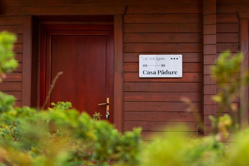 A wooden cabin with a sign indicating it is a 'Casa Pădure' and has a room number of 08-10.