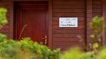 A wooden cabin with a sign indicating it is a 'Casa Pădure' and has a room number of 08-10.