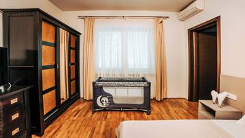 A hotel room with a bed, a desk, a wardrobe, and a window with curtains.