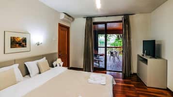 A hotel room with a large bed, a TV, a desk, and a balcony with outdoor furniture.