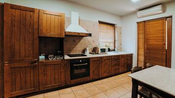 Una cocina con armarios de madera, estufa, microondas y una ventana con persianas.