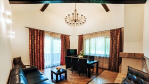 Ein Wohnzimmer mit einem schwarzen Ledersofa, einem Esstisch mit Stühlen und einer Kristallleuchter.
