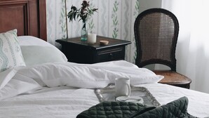 A neatly made bed with white bedding, a green quilt, and a tray with a mug and candle. - Burnima Cottage - situated next to Burnima Homestead at Historic Burnima Estate. (Bombala)