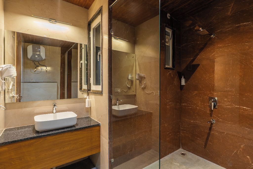Een moderne badkamer met een glazen douchecabine, een houten wastafelmeubel en een grote spiegel.