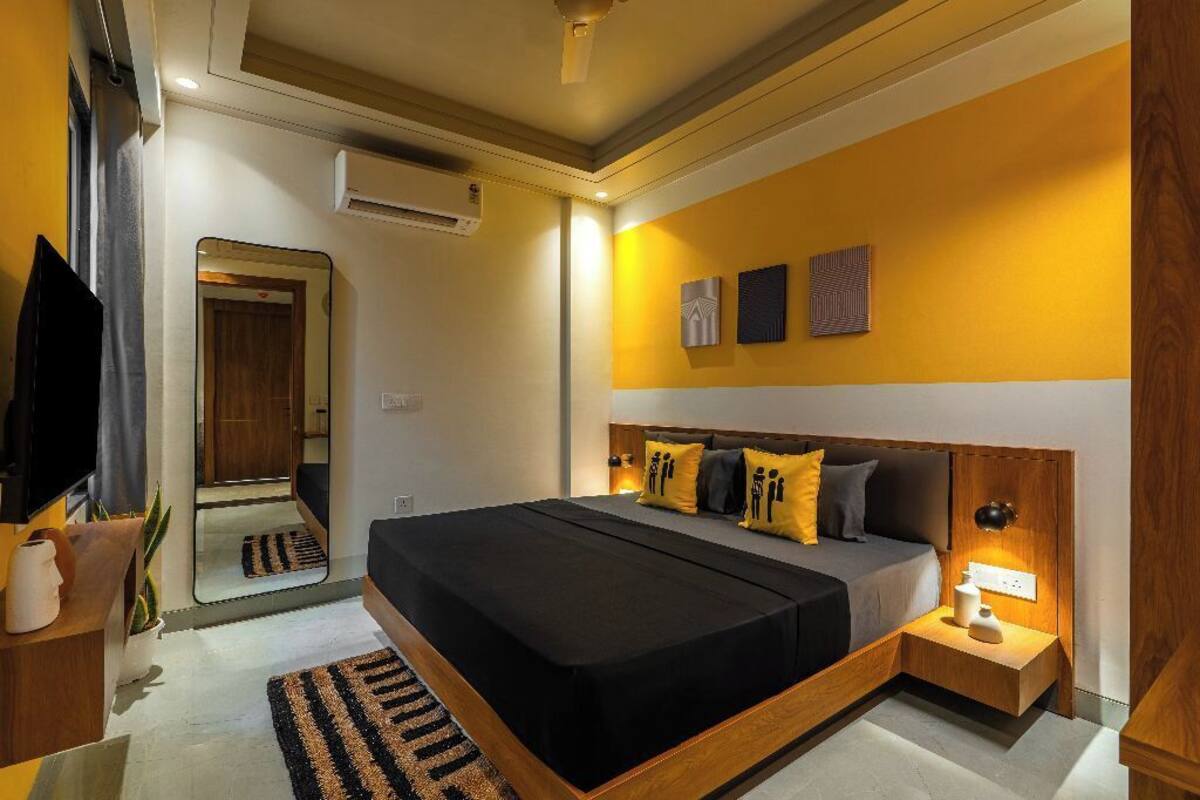 Une chambre à coucher moderne avec un grand lit, des tables de chevet, un miroir et des œuvres d’art accrochées au mur.
